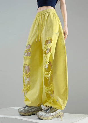 Yellow ripped pants worn by a person on a gray background