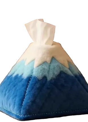 Blue and white mountain-shaped tissue box cover on a wooden surface with a blurred background