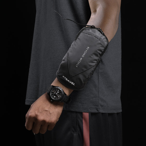 Person wearing a black travel pouch on their arm with a dark background