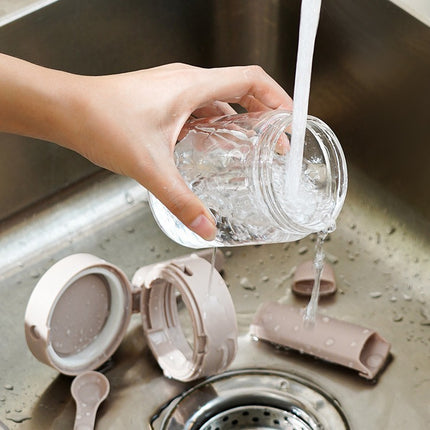 Person washing a glass jar over a sink with cleaning supplies nearby