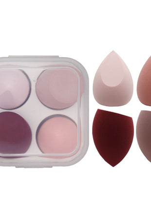 Makeup sponge applicators with a small container of makeup shades on a white background
