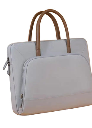 Light blue laptop bag with brown handles next to a silver laptop on an orange background