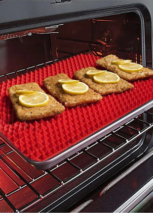 Red silicone baking mat with food items on an open oven