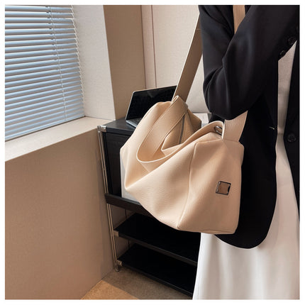 Person holding a beige handbag in an indoor setting