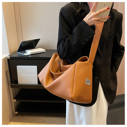 Person holding a brown handbag in an indoor setting