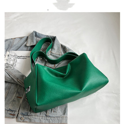 Green handbag on a denim jacket with a white background