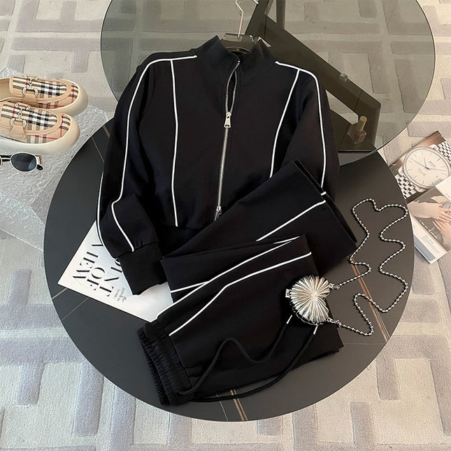 Black tracksuit with white piping on a round table with a magazine and sunglasses.