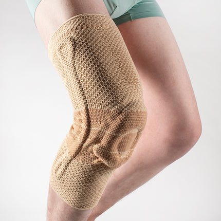 Knee brace on a person's leg against a plain background