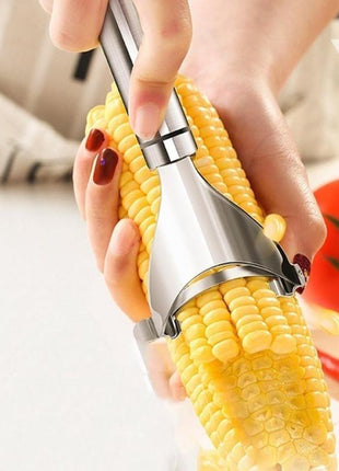 Corn on the cob being peeled with a metal corn shucker, with a blurred background.
