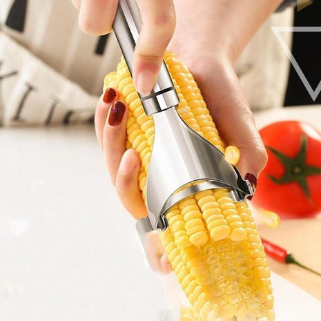 Corn on the cob being peeled with a metal corn shucker, with a blurred background.