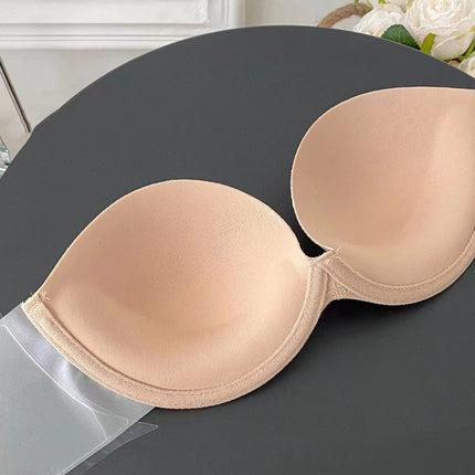 Beige strapless bra on a dark surface with white flowers in the background