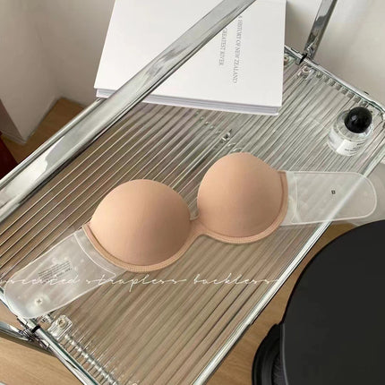 Nude-colored strapless bra on a clear plastic stand with a mirror in the background.