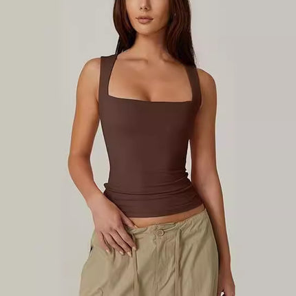 Woman wearing a brown tank top and beige pants against a plain background