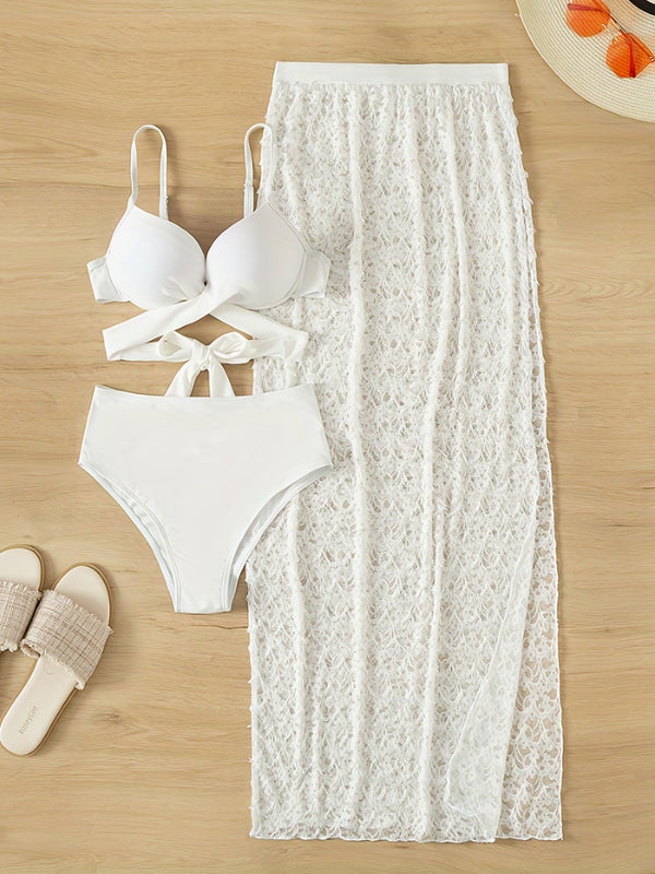White bikini set and lace skirt on a wooden surface with sandals.