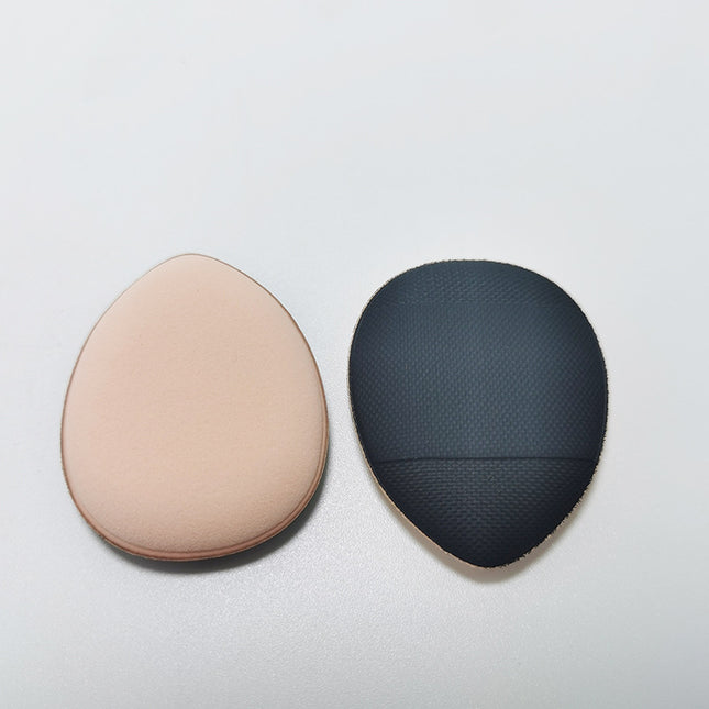 Two makeup sponges, one beige and one black textured, on a light gray background.