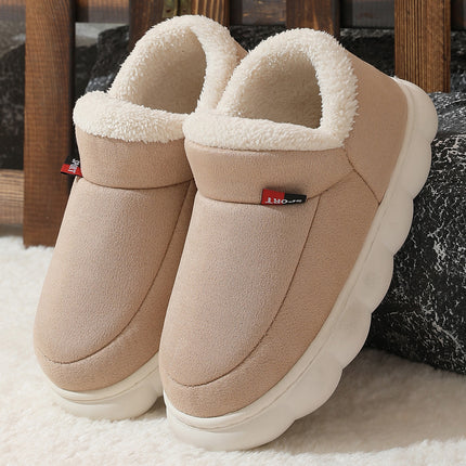 Pair of beige slippers with white fur lining on a soft surface.