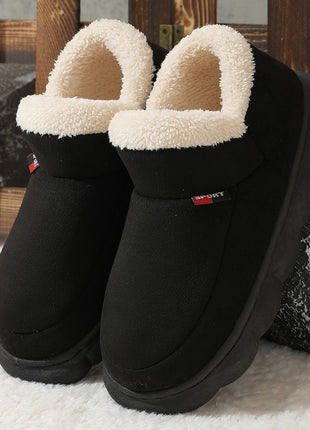 Black slippers with white fuzzy lining on a textured surface
