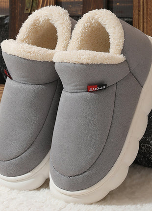 Gray slippers with white soles on a textured surface