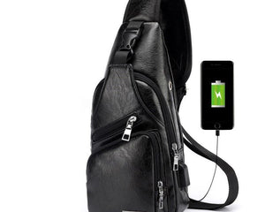 Black leather sling bag with USB charging port on a white background