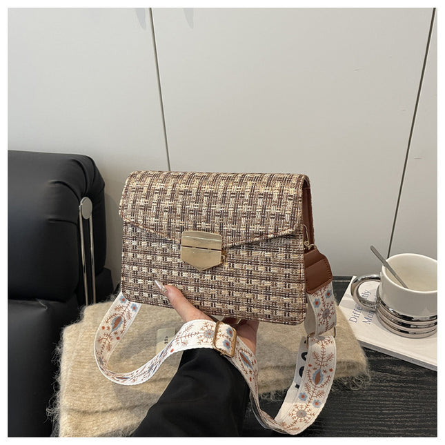 Handbag with a strap held by a person in an indoor setting