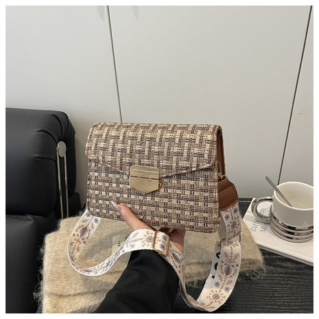 Handbag with a strap held by a person in an indoor setting