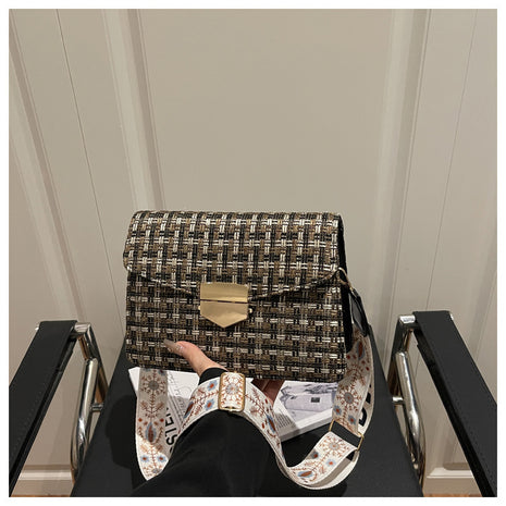Person holding a patterned handbag on a chair with a neutral background