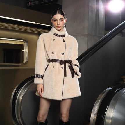 Model wearing a cream-colored coat with a belt in an urban setting
