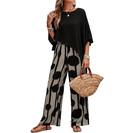 Woman wearing a black top and polka dot pants holding a straw bag outdoors.