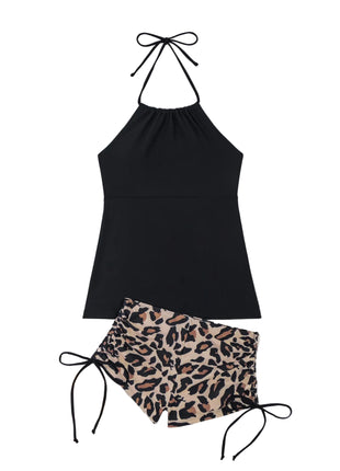 Black halter top and leopard print shorts on a white background with a hat and palm leaf.