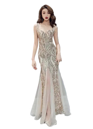 Woman in a glamorous evening gown standing in front of a reflective black and gray geometric wall.