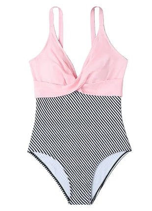 Pink and black striped swimsuit on a gray surface with a hat and newspaper.