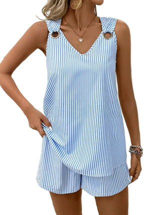 Woman wearing a blue and white striped dress with cut-out shoulder straps, standing against a white background.