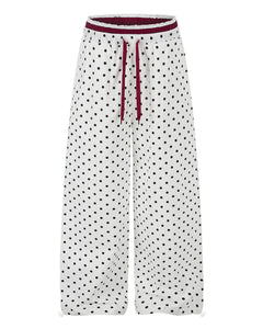 Women's ruffle-trimmed polka dot straight-leg pants featuring a mid-rise waist and cotton fabric.