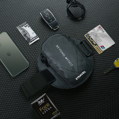 Black waist bag with 'Etravel' branding on a textured black surface with various items around it.