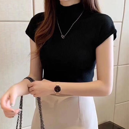 Person wearing a black sleeveless top and a watch, with a neutral background