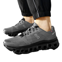 Gray athletic shoes with unique sole design worn outdoors on a paved surface