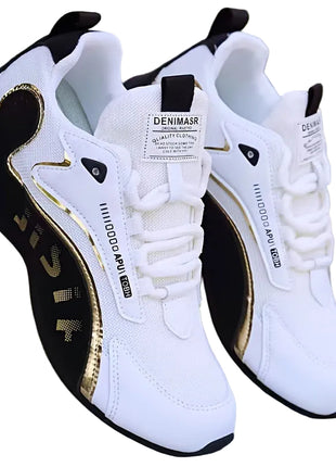 White sneakers with black and gold accents on a blurred natural background blndl