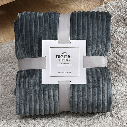 Folded gray textured blanket with a white label on a carpeted floor.