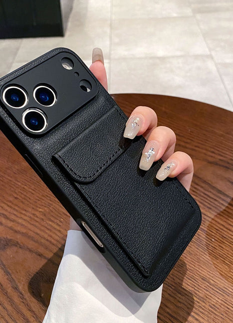 Black phone case with card holder held by a hand on a wooden table.