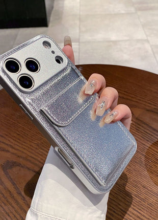 Silver phone case with card holder held by a hand on a wooden table.