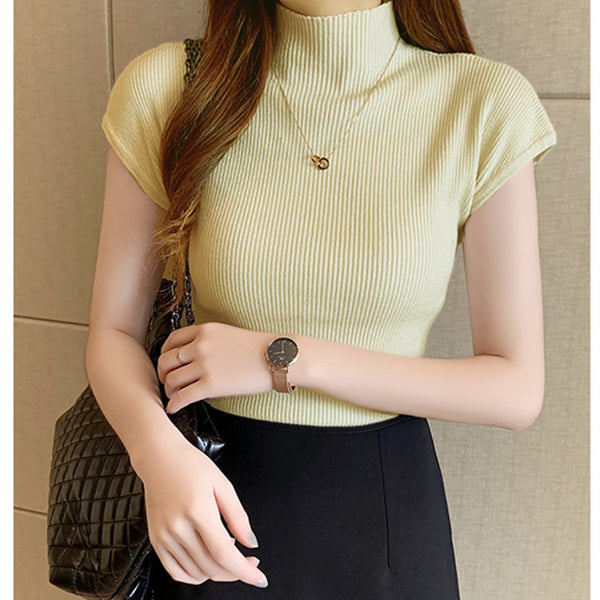 Woman wearing a light green ribbed top with a neutral background
