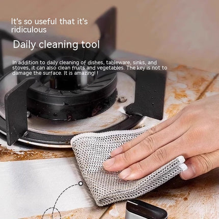 Person cleaning a stove with a mesh cleaning tool on a kitchen counter.