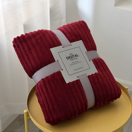 Folded red blanket with a white tag on a yellow surface
