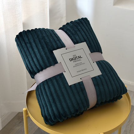 Folded teal blanket with a label on a yellow stool against a light curtain background